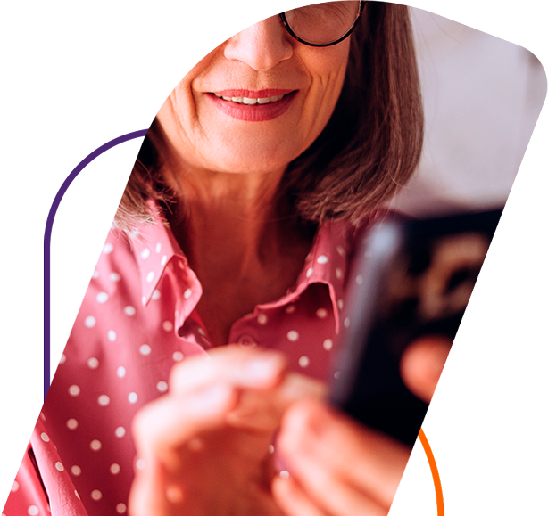Mulher olhando para tela do celular e sorrindo com a facilidade de contratar o Seguro Bmg