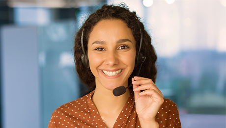Mulher atendente de telemarketing sorrindo com a mão no headset