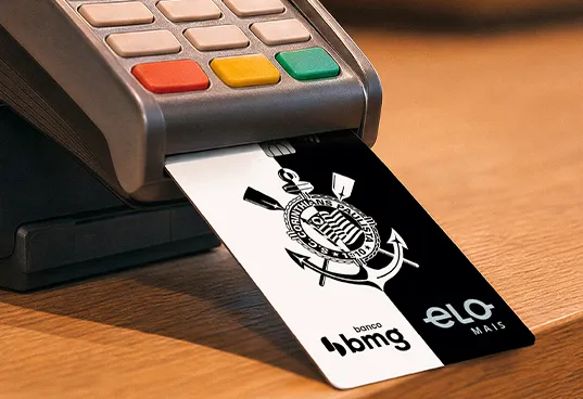 Cartão de crédito sem taxas da conta digital do Corinthians Bmg sendo inserido em uma máquina de pagamento
